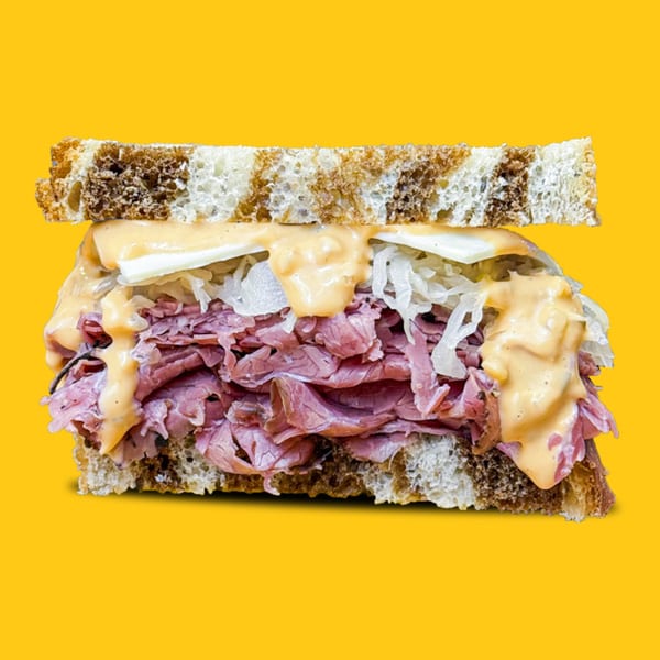 Jay's Deli pastrami sandwich with sauerkraut, cheese, and sauce on rye bread.