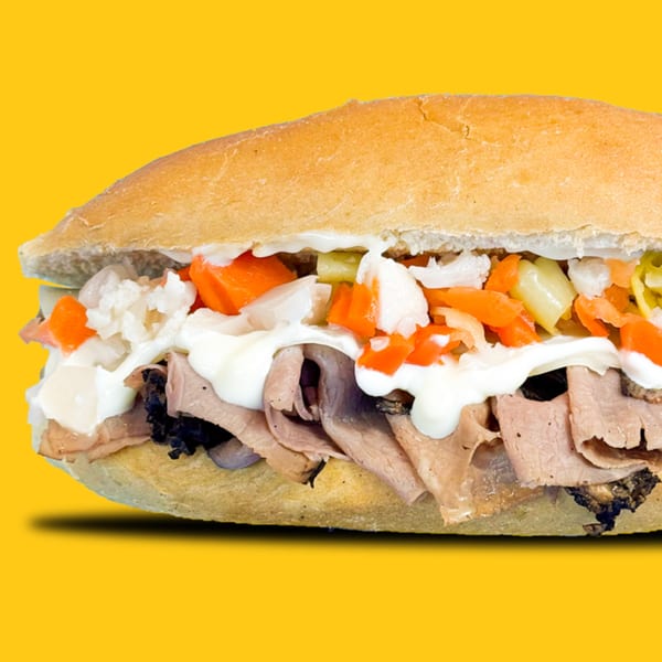Jay's Deli sandwich with sliced meat, white sauce, and chopped vegetables on a yellow background.